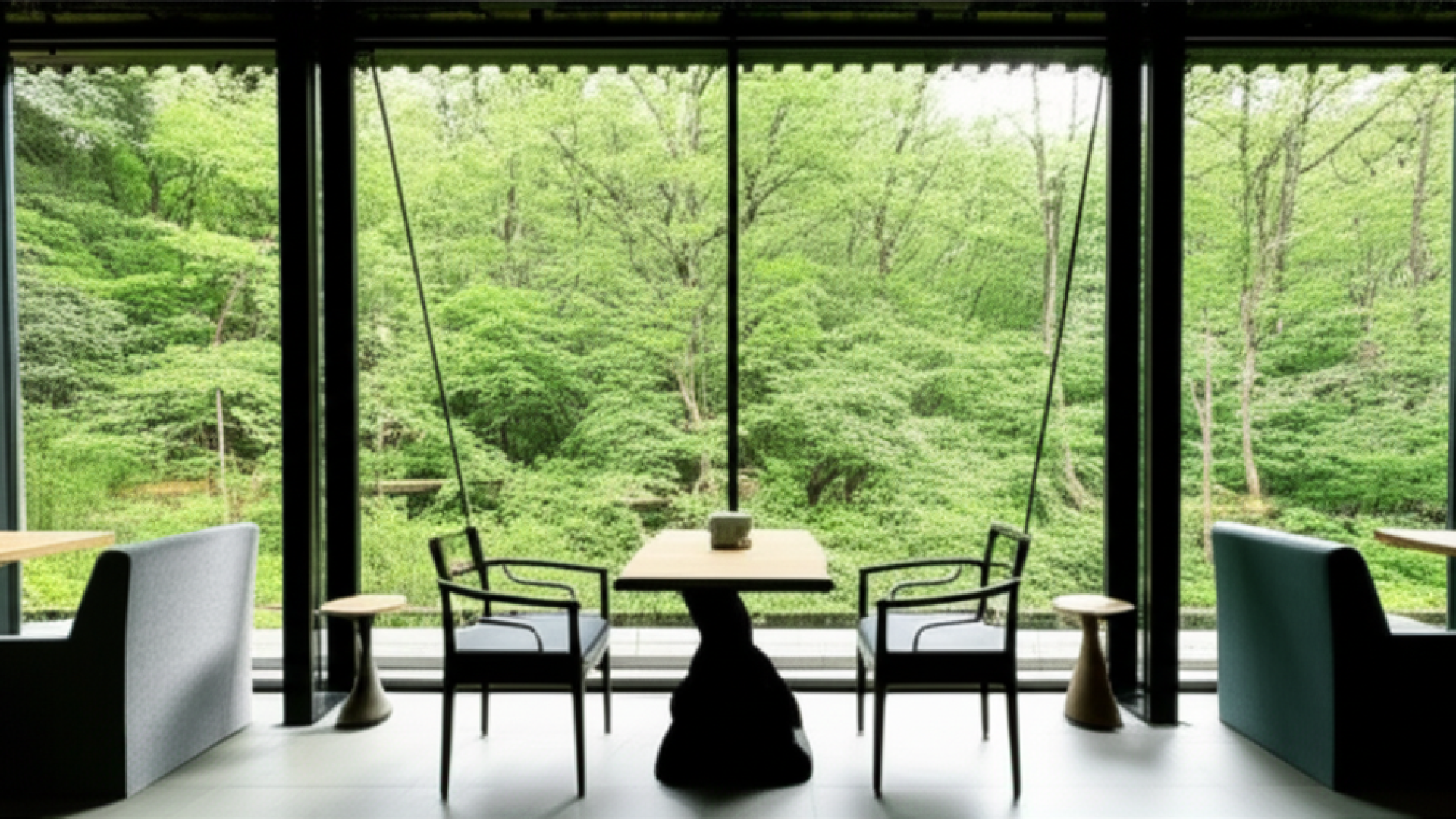 A modern, minimalist cafe interior with expansive floor-to-ceiling glass windows showing a panoramic
